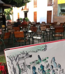 Eine Café-Szene wird gezeichnet. Im Hintergrund das Café mit Stühlen und Tischen.